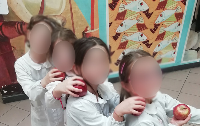 Bambine in fila indiana che tengono in mano una mela