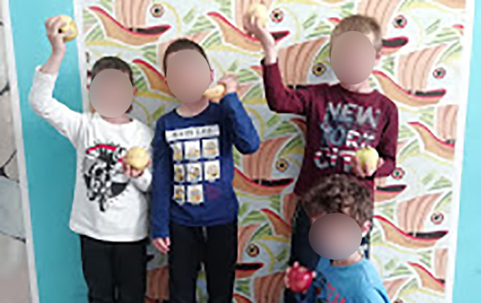 Quattro bambini che tengono in mano della frutta