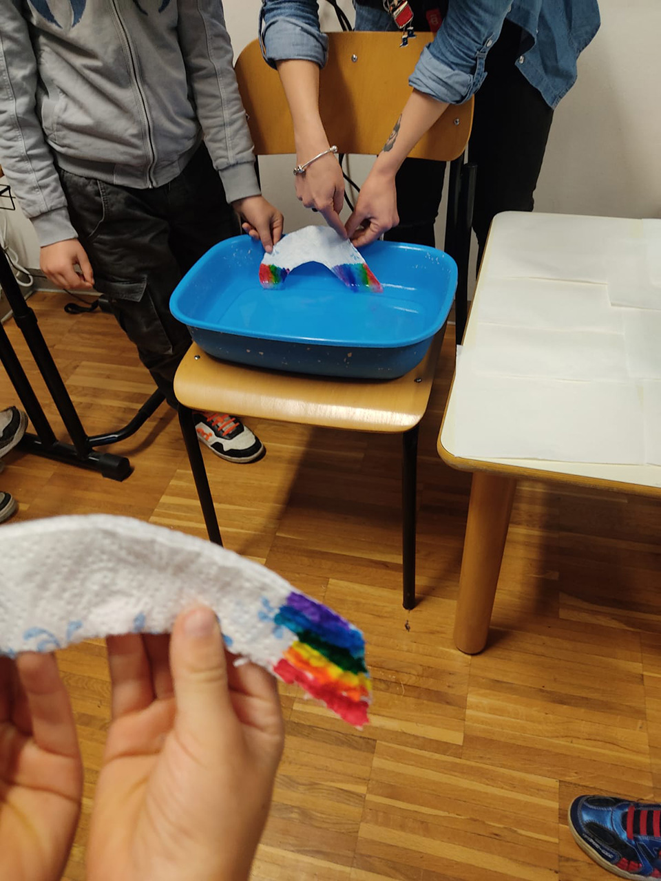 bambino accanto a sedia su cui c’è una bacinella con acqua. bambino immerge disegno bambino accanto a sedia su cui c'è una bacinella con acqua. bambino immerge disegno